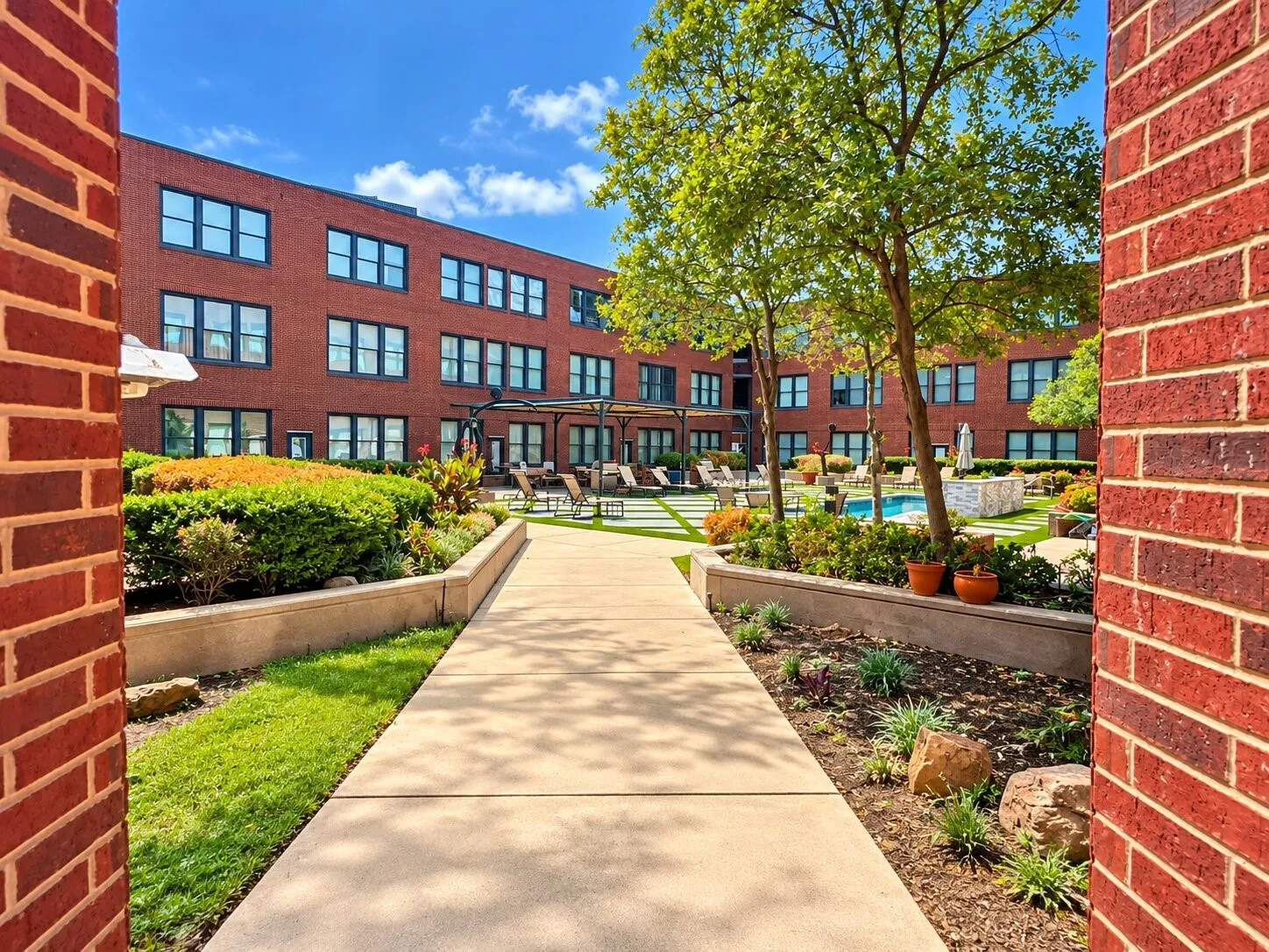 Courtyard featuring a swimming pool, paved walkway, brick facade architecture, and manicured landscaping