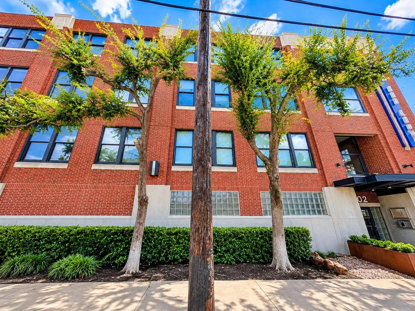 Red brick exterior featuring multi-pane windows, concrete masonry accents, and decorative glass block detailing