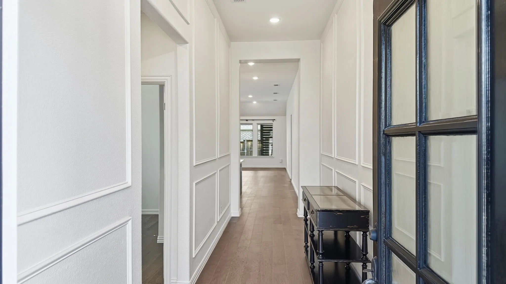 Entryway featuring wainscoting detail, wood-finish flooring, recessed lighting, and a multi-pane glass-inset door