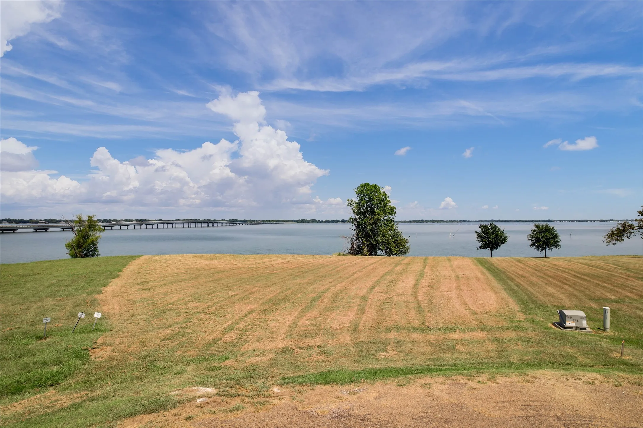 Waterfront acreage featuring expansive grassy terrain, mature trees, and direct water access