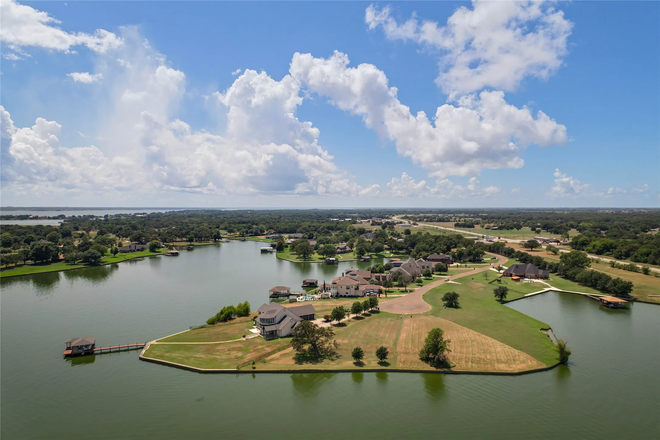 Waterfront estate featuring a private dock, extensive shoreline, multi-level residence, and paved circular driveway