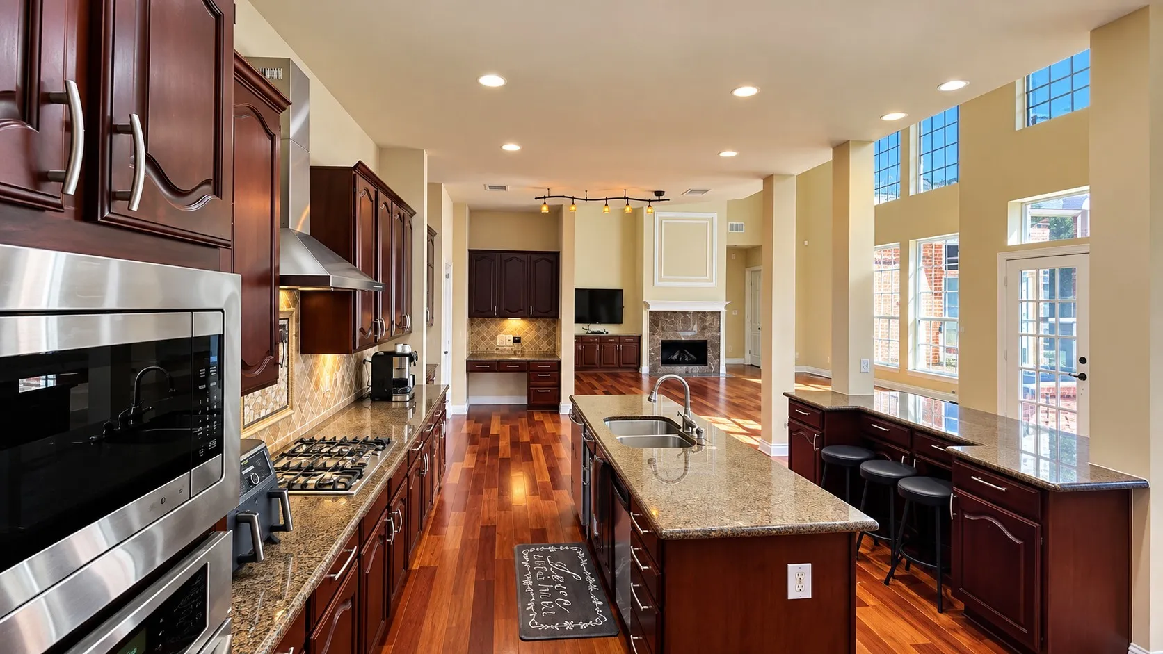 Gourmet kitchen with rich wood cabinetry, stainless steel appliances, and a central island with a built-in sink