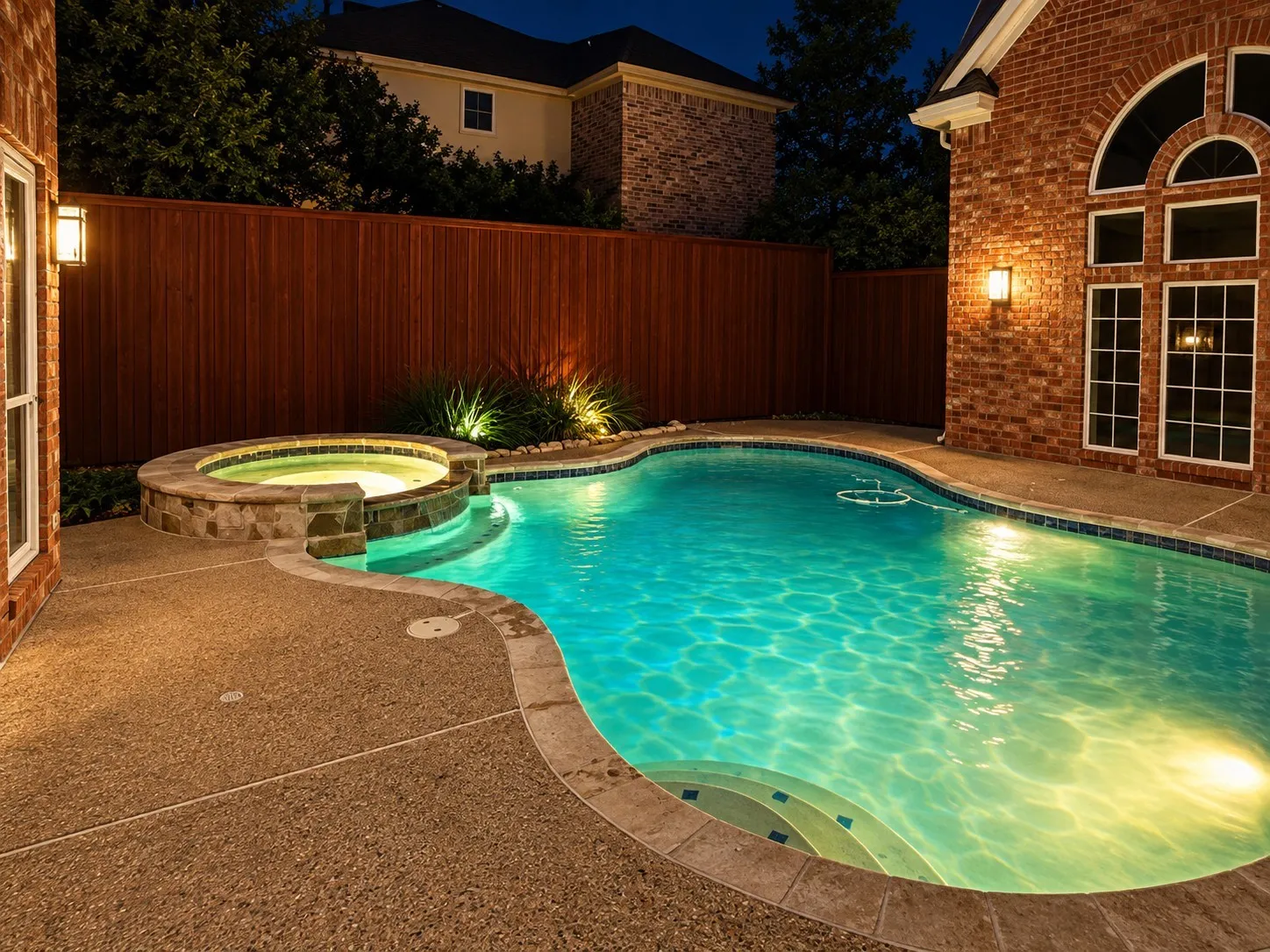 Curved swimming pool with integrated spa and stone surround