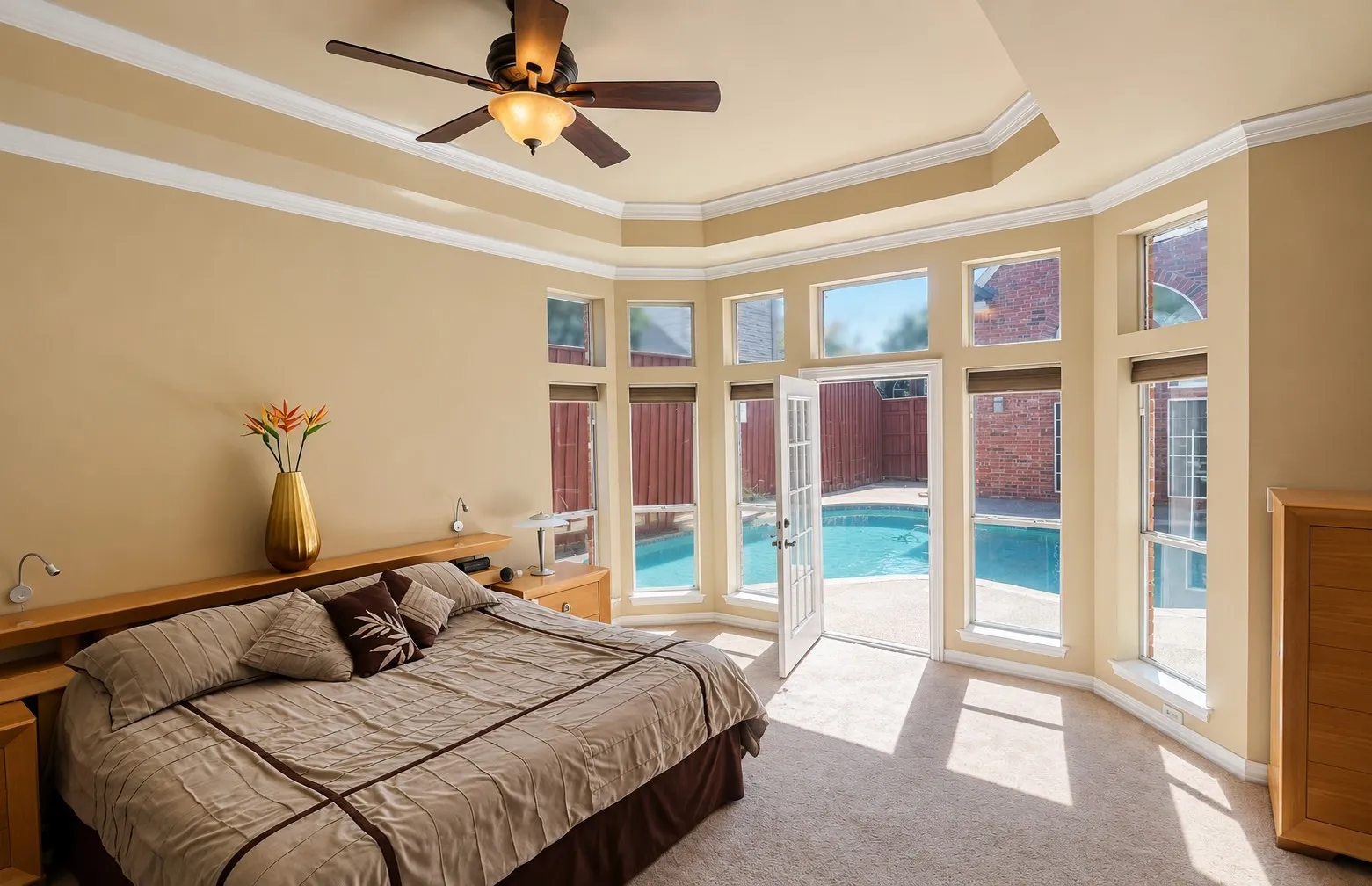 Tray ceiling with a ceiling fan, bay window with multiple panes, double French doors, and direct access to a swimming pool