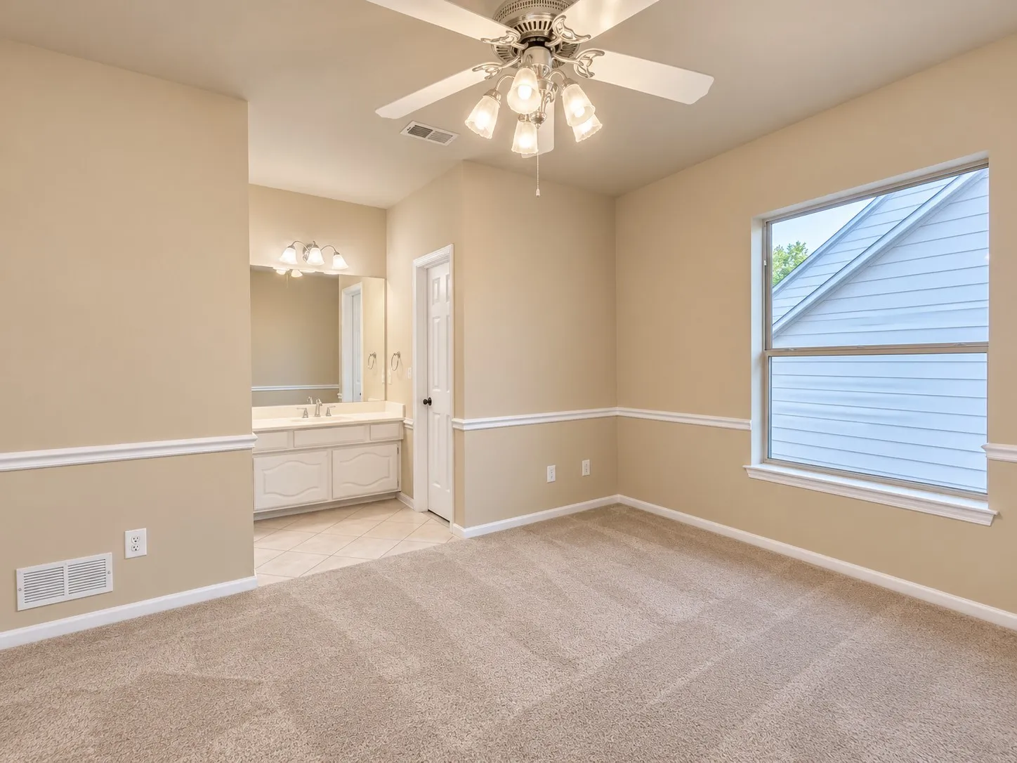 Carpeted room with a ceiling fan light fixture, a large window, and decorative wall molding