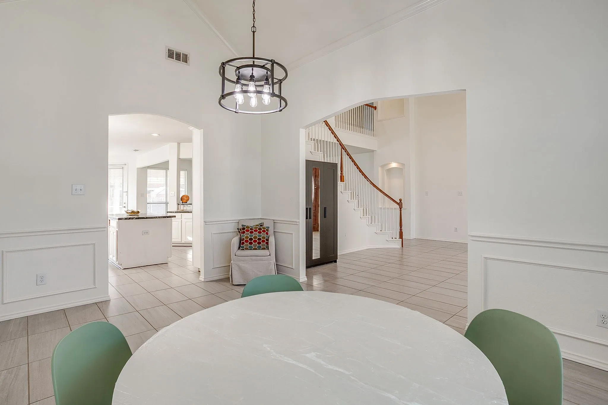 Kitchen featuring white cabinetry, a central island with dark stone countertops, stainless steel double wall ovens, a  tile backsplash, and ceramic tile flooring