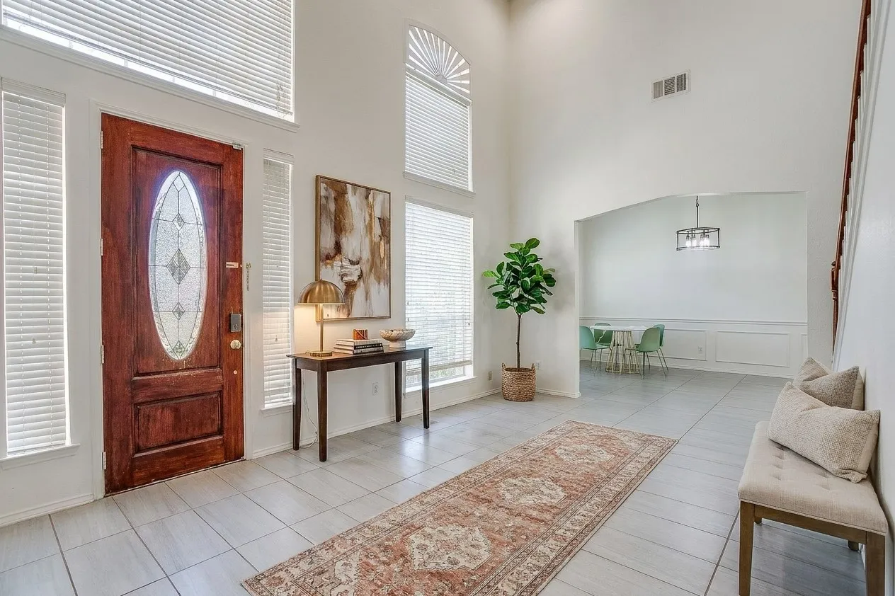 Two-story foyer featuring tile flooring, a staircase with wooden handrails,, and a floor-to-ceiling tile-surround fireplace