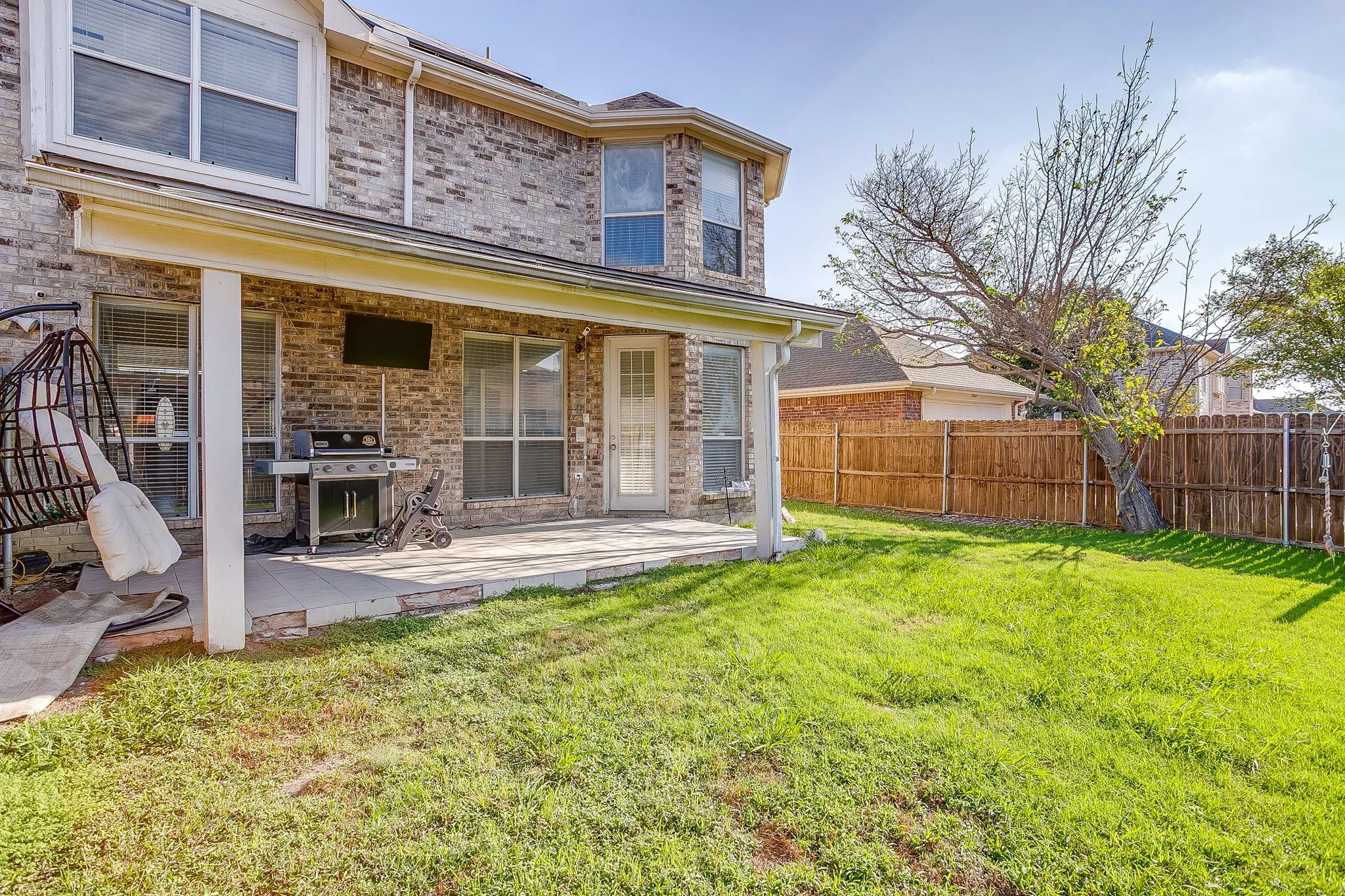 Brick exterior with a covered rear patio, fenced backyard