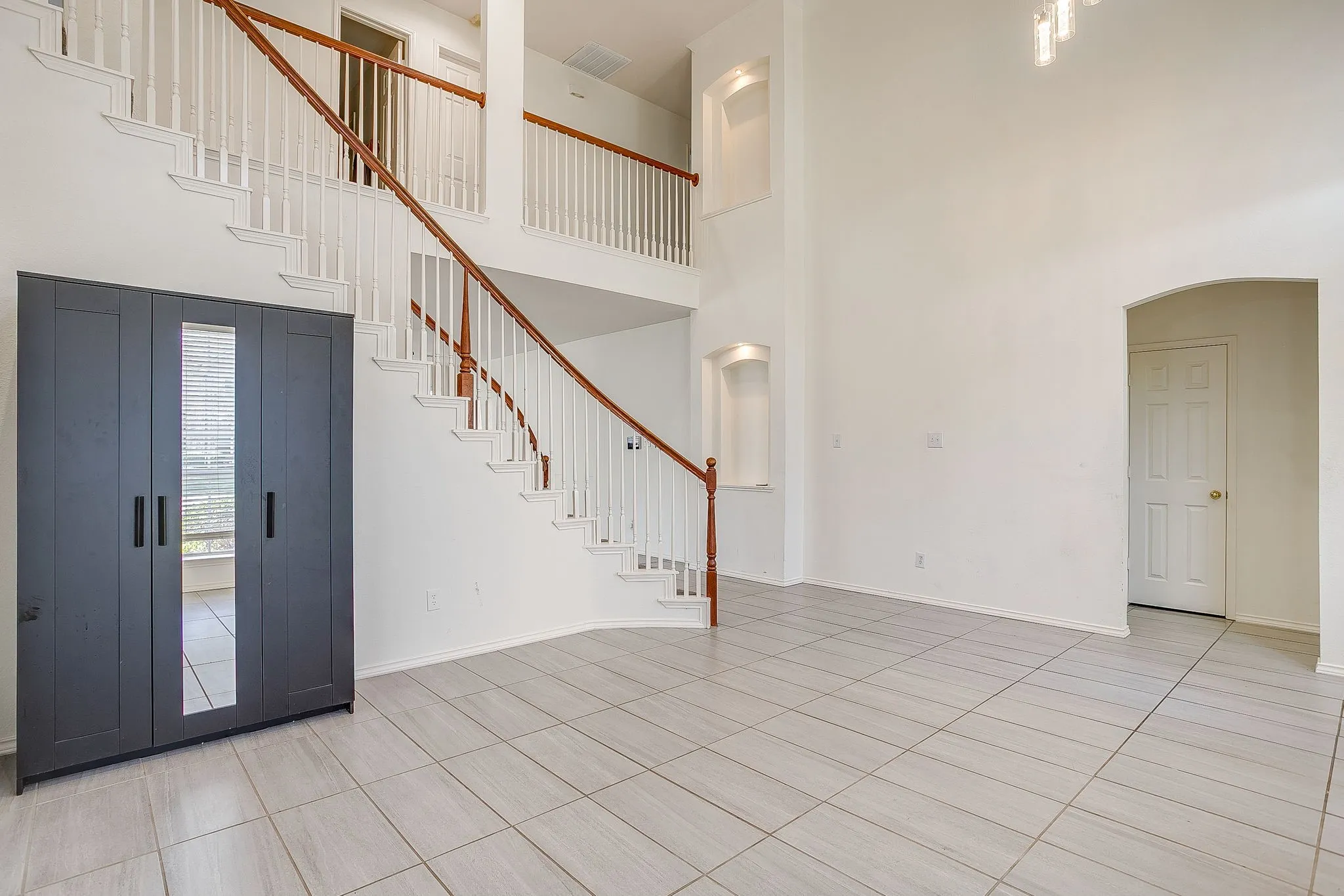 Vaulted ceilings, neutral tile flooring, decorative wall wainscoting, arched architectural detailing.