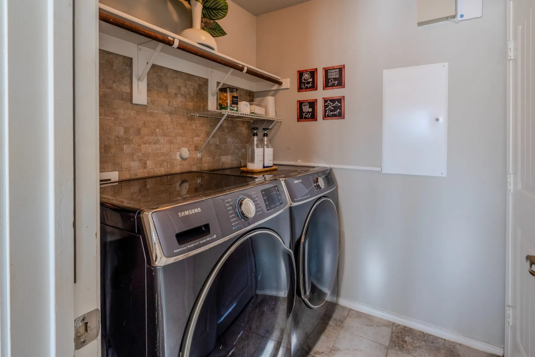 Laundry room featuring stone-tile backsplash, built-in shelving, and tile flooring