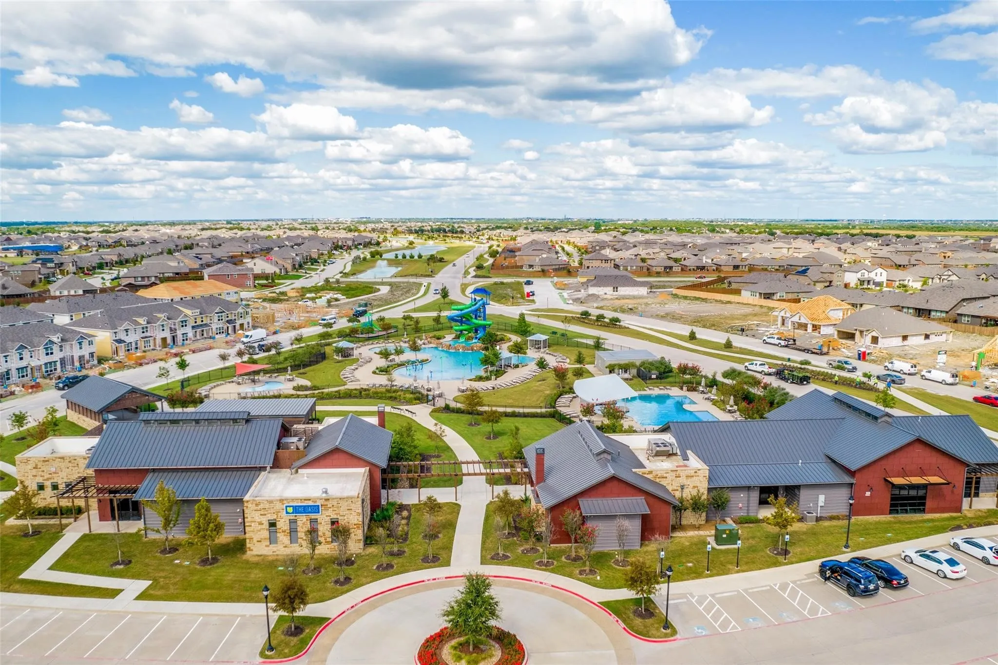 Community recreation center featuring multiple swimming pools, a water slide, landscaped grounds, and dedicated parking
