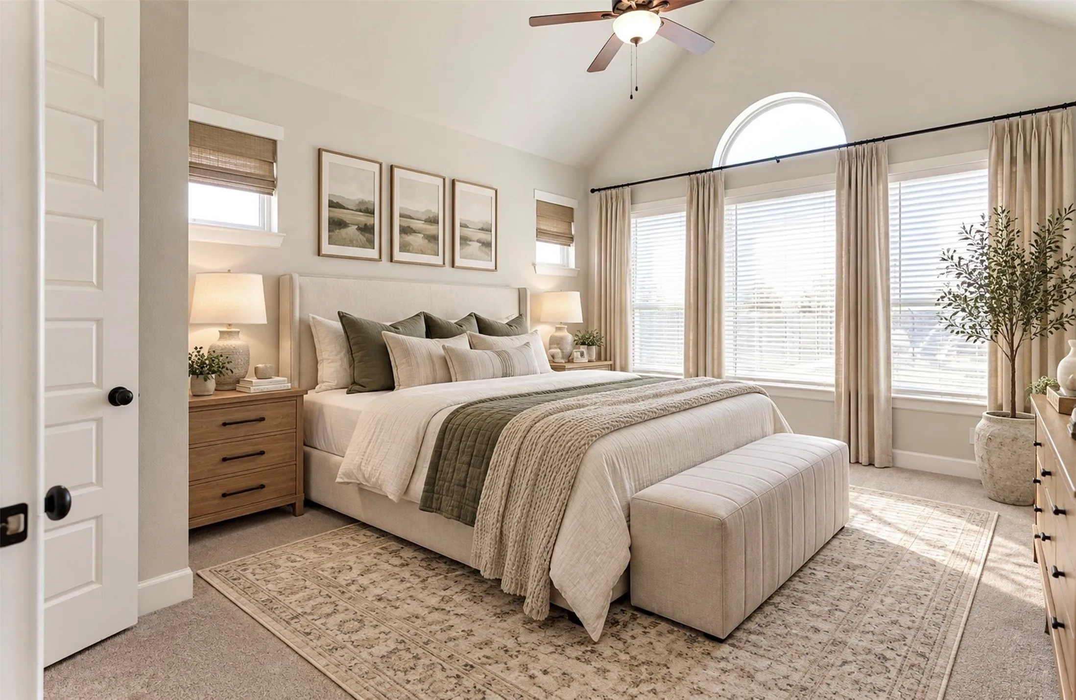 Vaulted ceiling featuring a central ceiling fan and arched window accent, neutral carpeting, and multi-pane window configuration