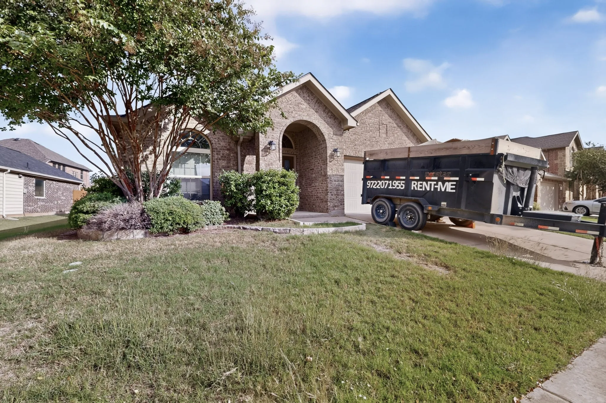 Brick exterior residence featuring an arched entryway, gabled roofline, and front landscaping