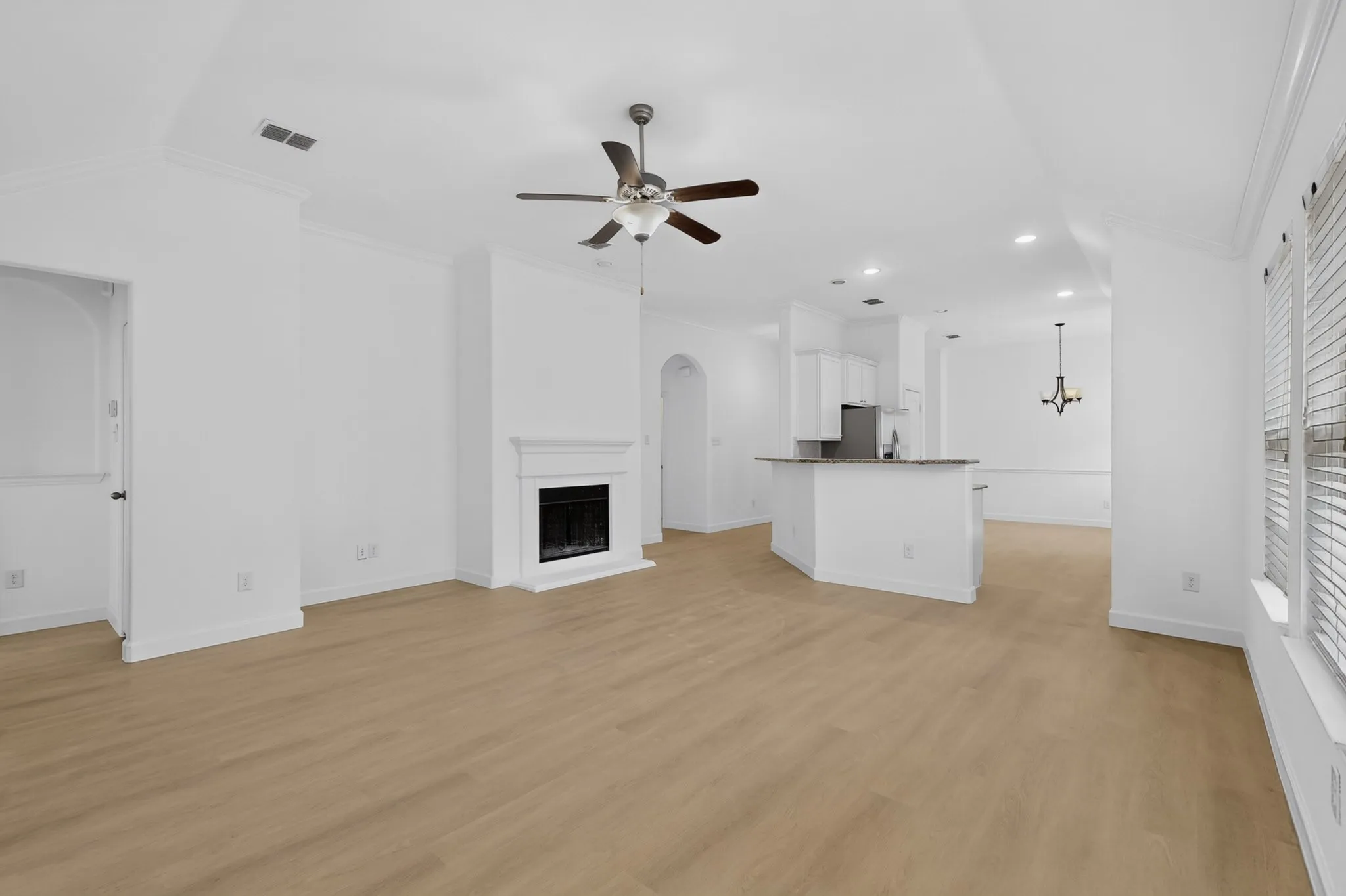 Vaulted ceilings, wood-finish flooring, fireplace with a mantle, recessed lighting, and a kitchen peninsula with cabinetry