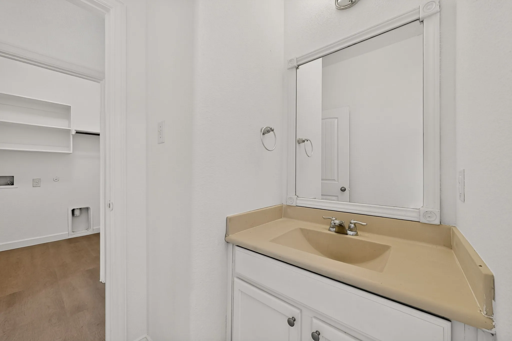 Vanity featuring a molded countertop with integrated sink, white cabinetry, wall-mounted mirror, and metal hardware