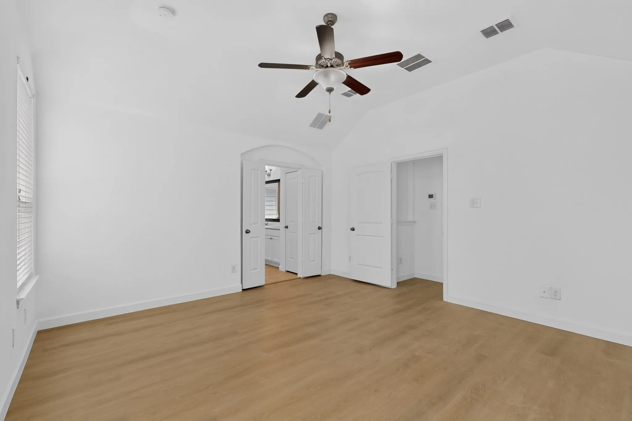 Vaulted ceilings, wood-finish flooring, and a ceiling fan with integrated lighting