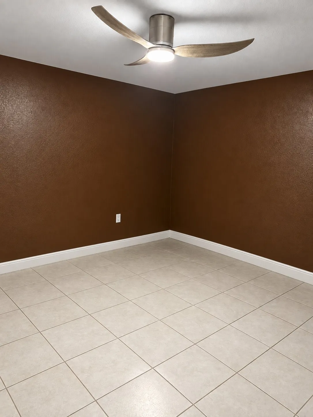 Ceramic tile flooring, textured wall finish, and a modern three-blade ceiling fan with an integrated light fixture