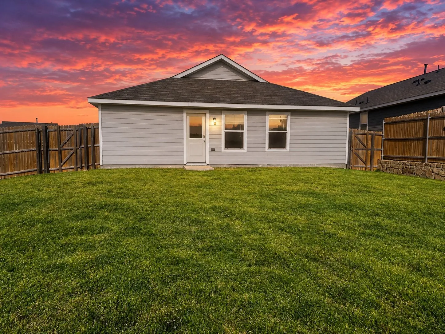 Exterior featuring horizontal lap siding, a pitched roofline, an expansive lawn, and enclosed wood privacy fencing