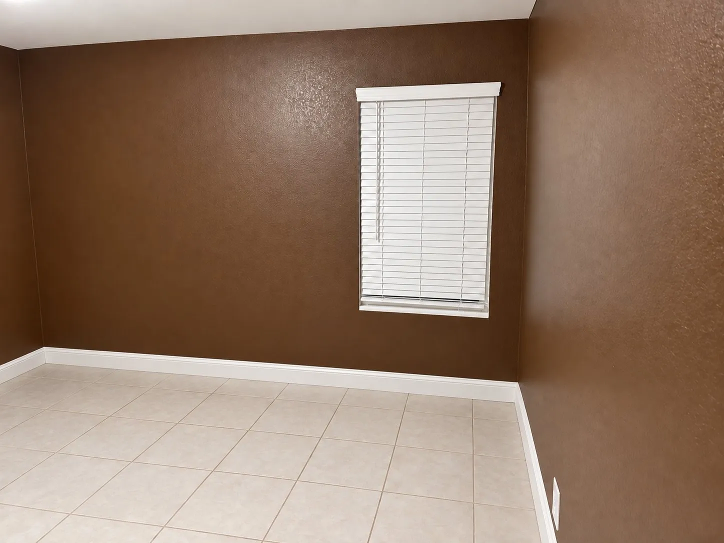 Room featuring smooth-texture walls, ceramic tile flooring, and a window with horizontal blinds