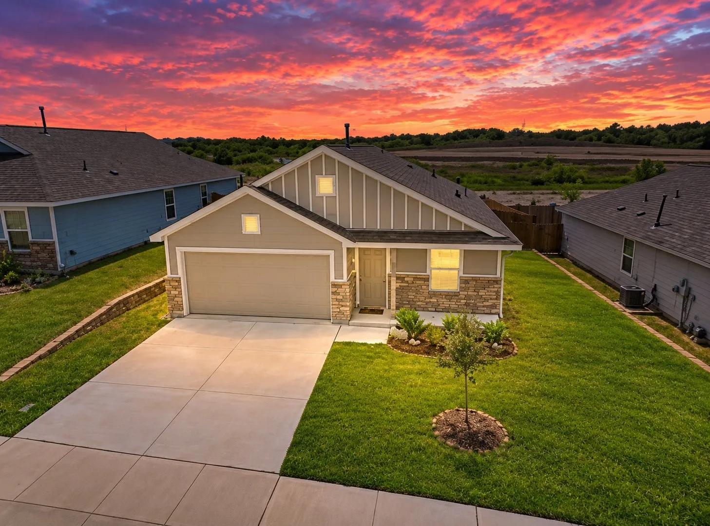 Single-story residence featuring vertical siding, stone masonry accents, an attached two-car garage, and a paved concrete driveway