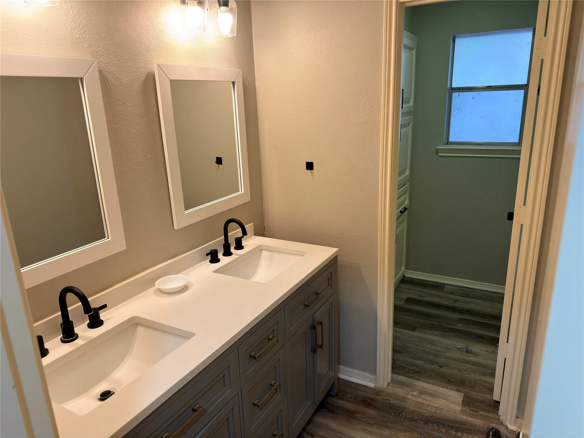 Dual-sink vanity with a solid-surface countertop, undermount basins, matte black widespread faucets, and framed wall mirrors