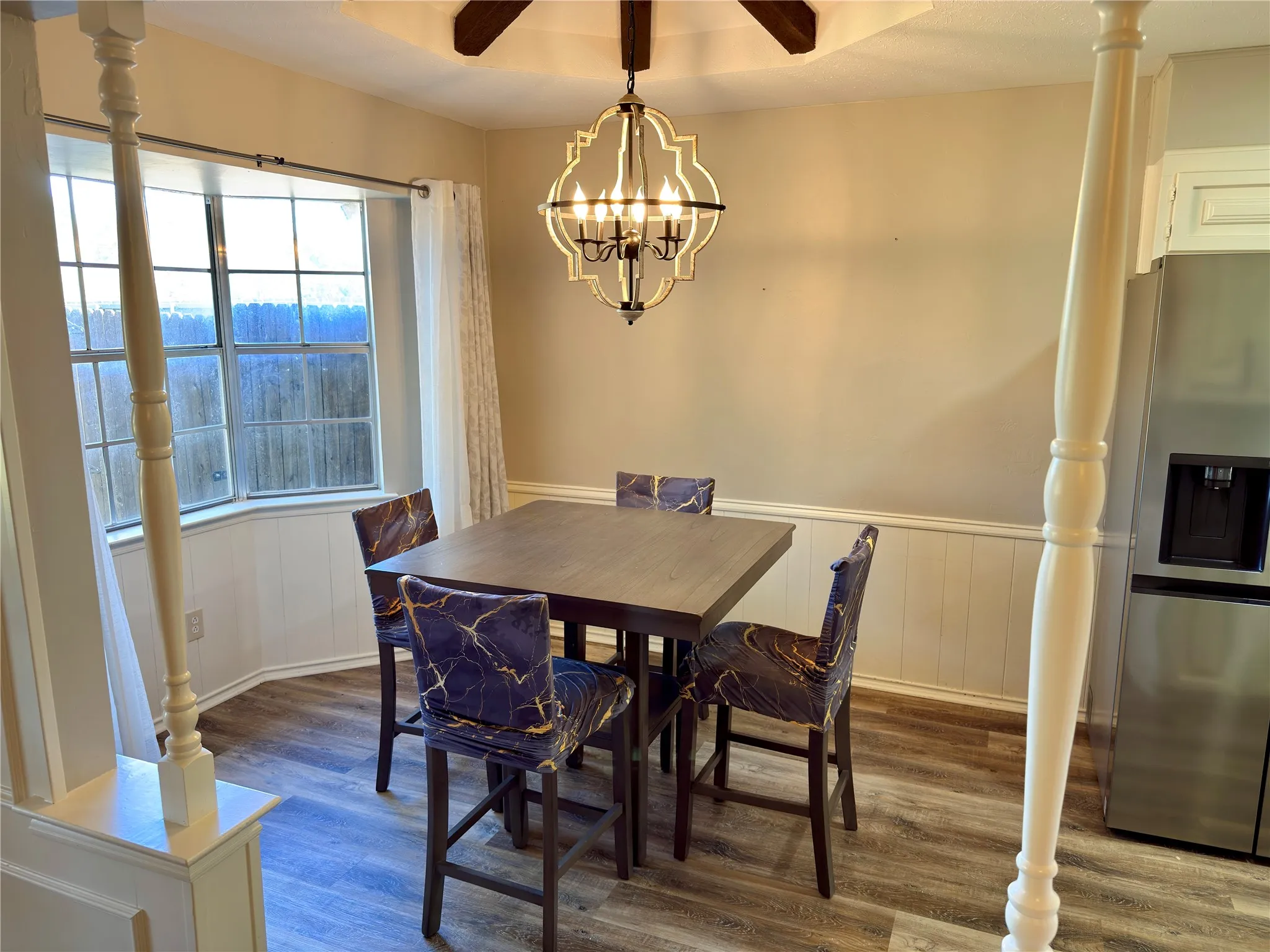 Bay window featuring multi-pane glass, wood-finish flooring, wainscoting, and a geometric metal pendant light fixture