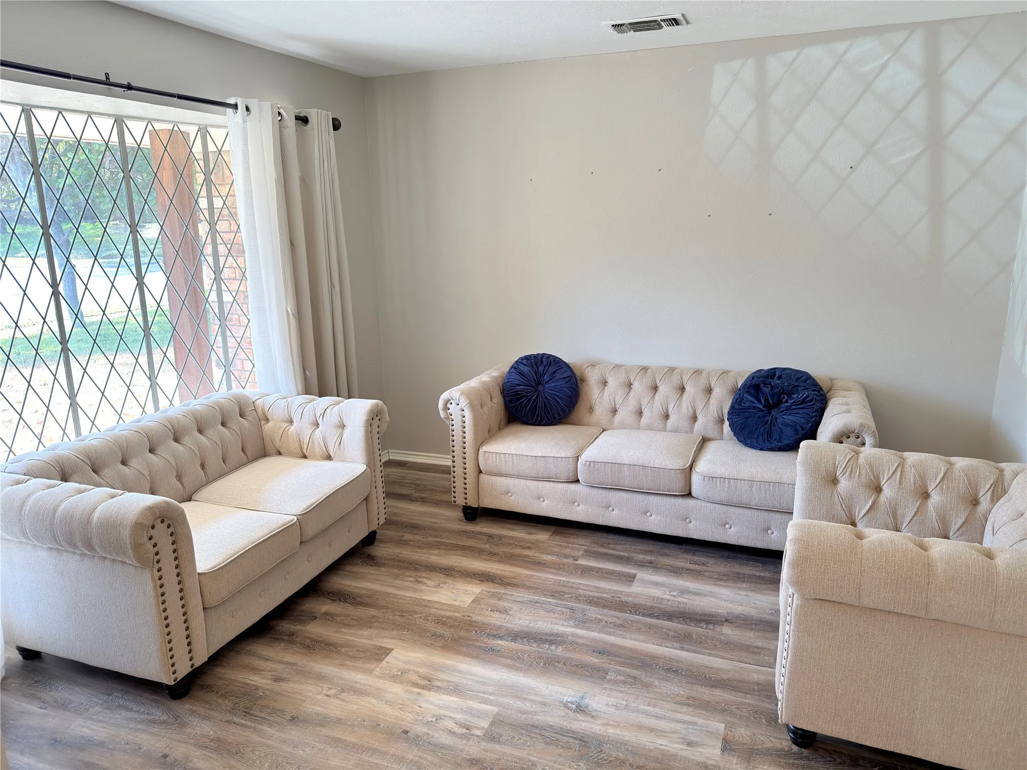 Wood-finish flooring and floor-to-ceiling windows featuring diamond-patterned mullions