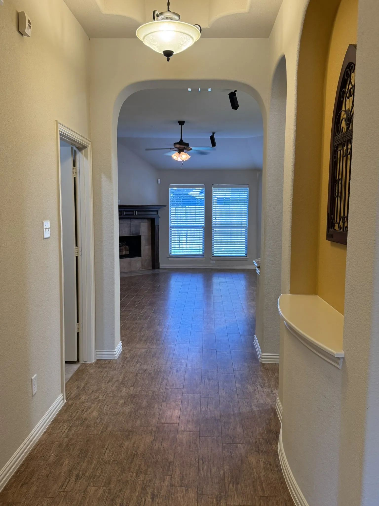 Entryway featuring wood-finish flooring, an arched architectural alcove with a built-in display shelf, a recessed ceiling tray, and a semi-flush mount light fixture