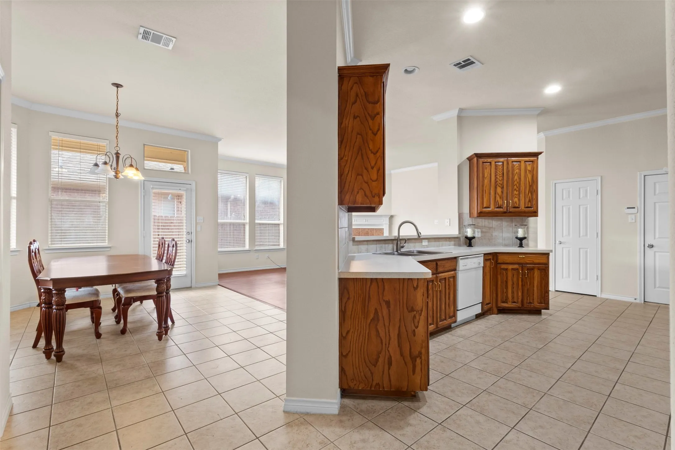 Kitchen featuring stained wood cabinetry, solid surface countertops, and white appliances, complemented by tile flooring and crown molding