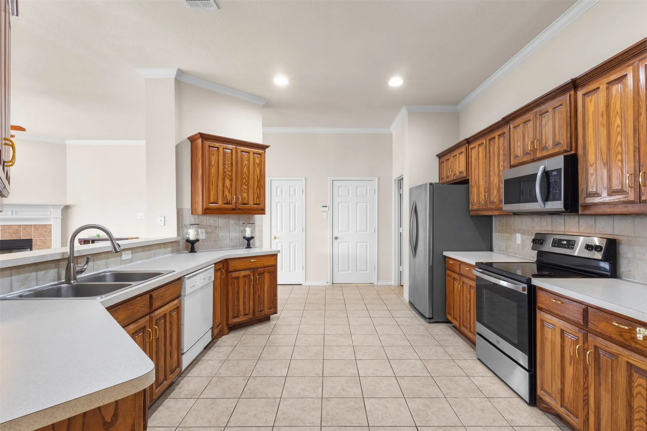 Kitchen featuring stained wood cabinetry, solid surface countertops, tile flooring, recessed lighting, and stainless steel appliances