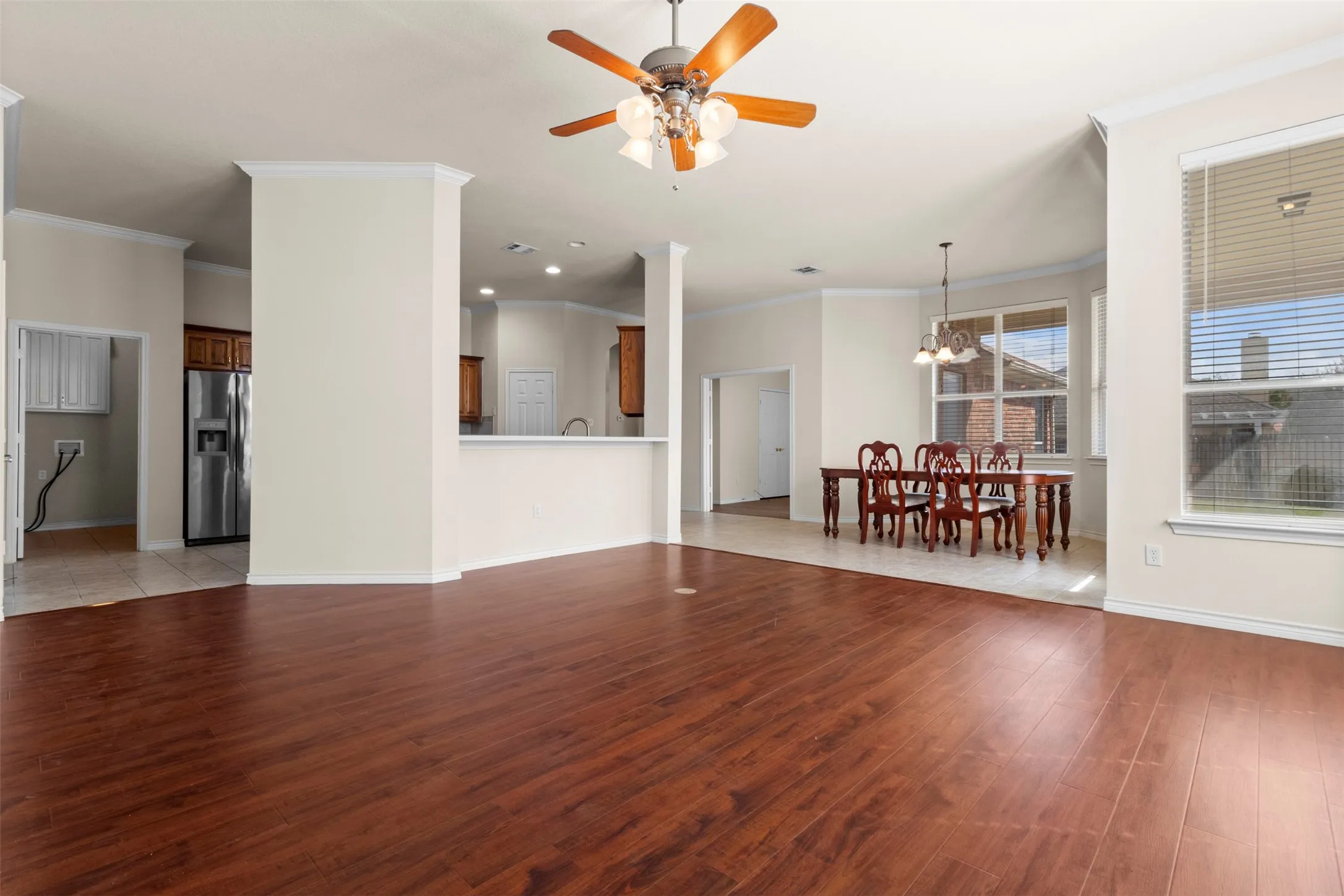 Open-concept floor plan featuring wood-finish flooring, recessed lighting, a ceiling fan, and multi-pane windows with horizontal blinds