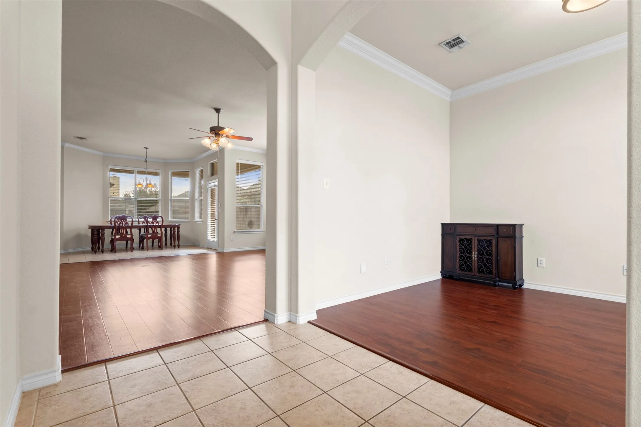 Arched architectural openings, neutral wall palette, crown molding, and wood-finish flooring