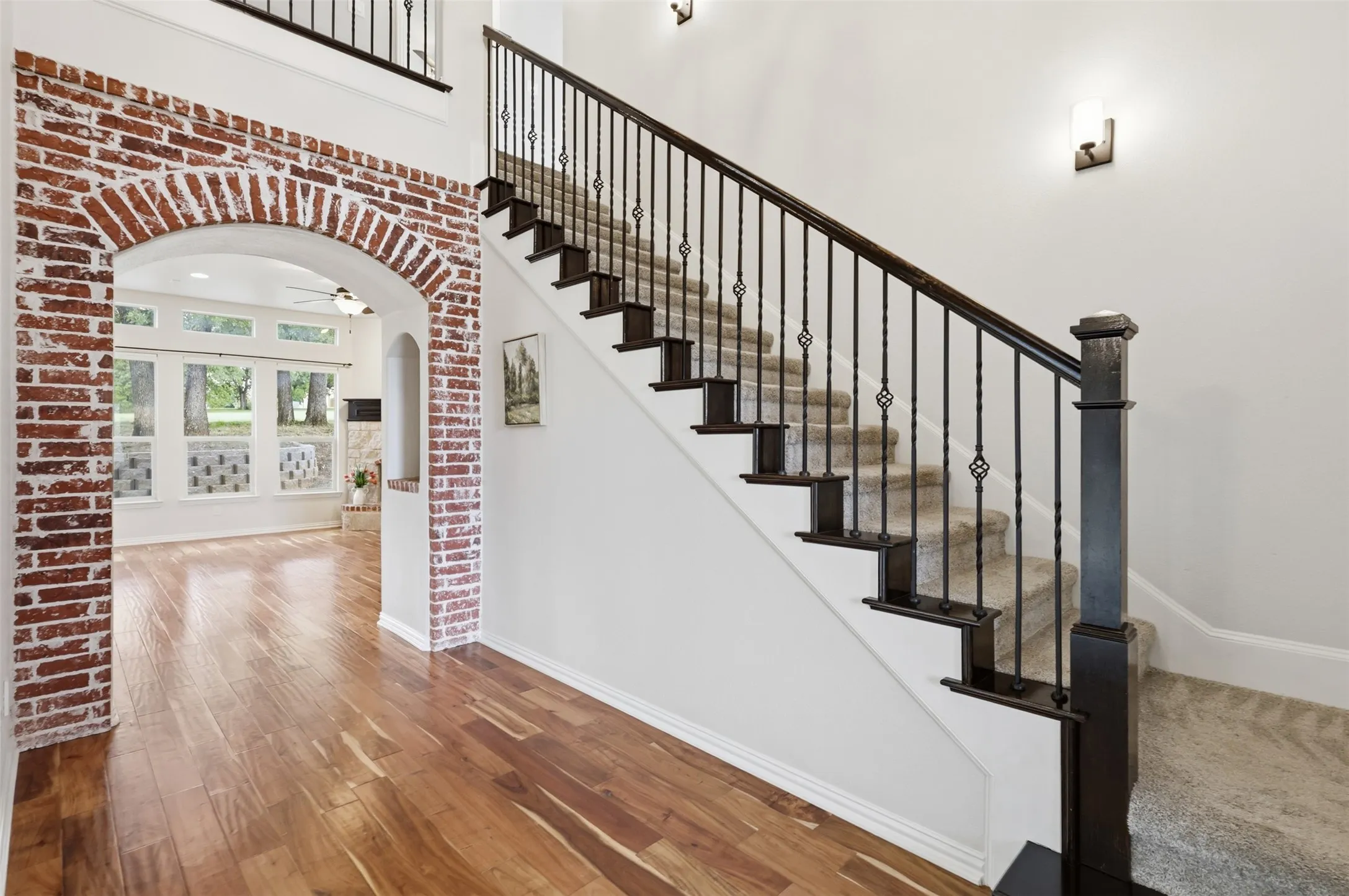 Staircase featuring a dark wood handrail, metal balusters, and carpeted treads