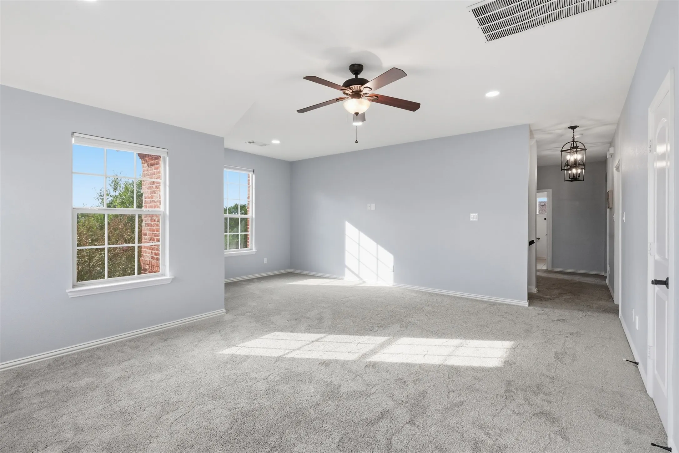 Neutral-toned interior featuring wall-to-wall carpeting, recessed lighting, a multi-blade ceiling fan with integrated lighting, and multipane windows