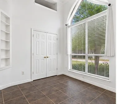High ceilings, floor-to-ceiling arched window, tile flooring, and built-in wall shelving