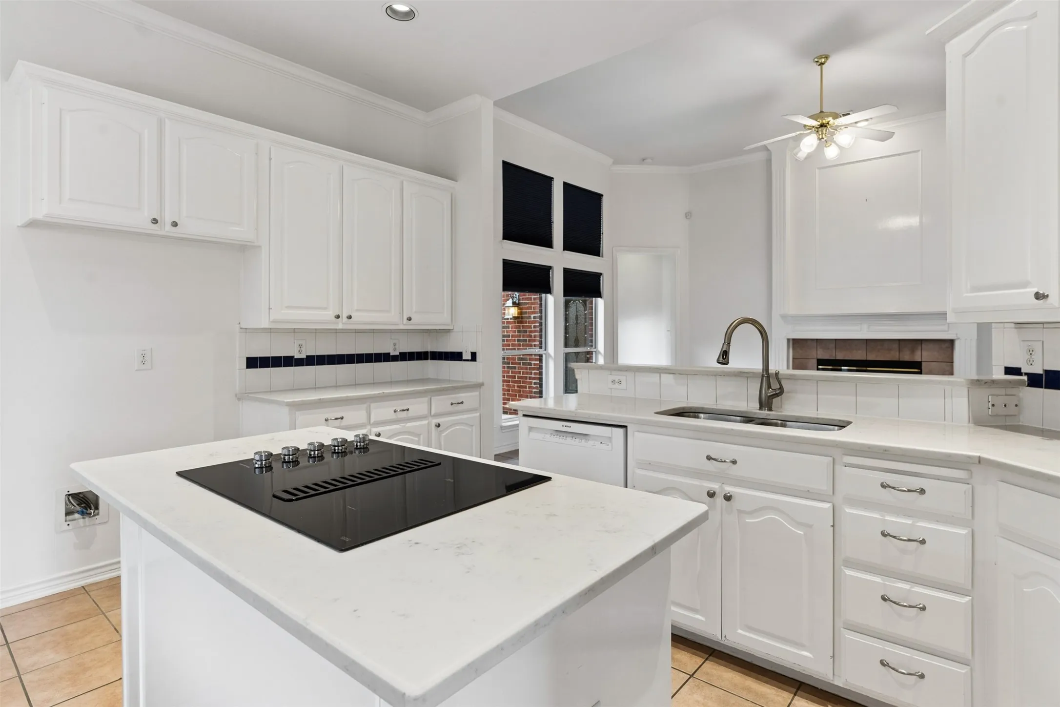 Kitchen featuring white shaker-style cabinetry, quartz countertops, a central island with an integrated induction cooktop, and tile flooring