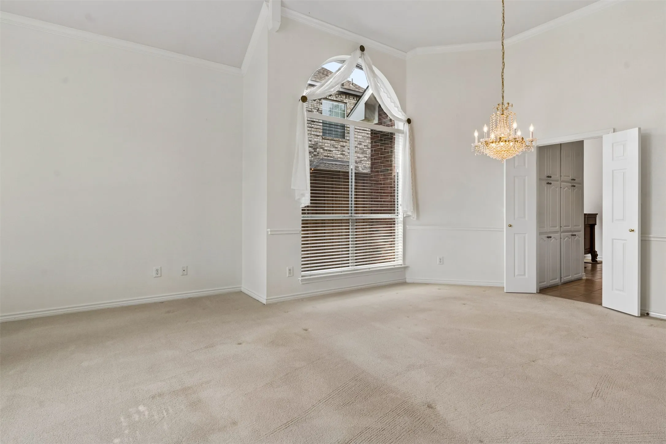 High ceilings, arched top window, crystal-style chandelier, and built-in cabinetry