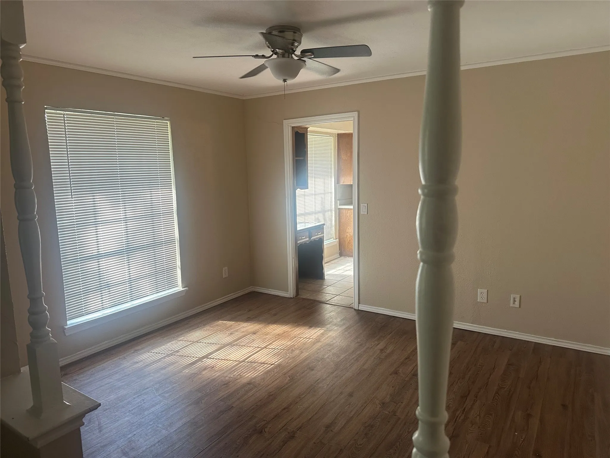 Interior room featuring wood-finish flooring, a ceiling fan, and prominent decorative columns