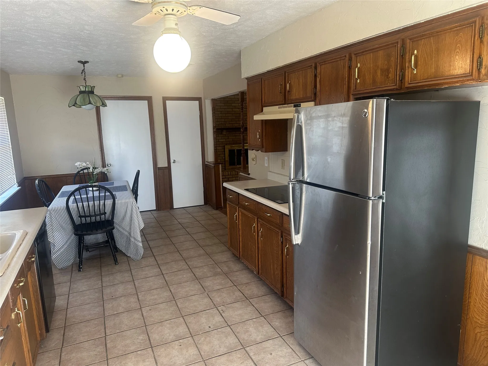 Kitchen featuring wood cabinetry, stainless steel refrigerator, tile flooring, and integrated lighting fixtures