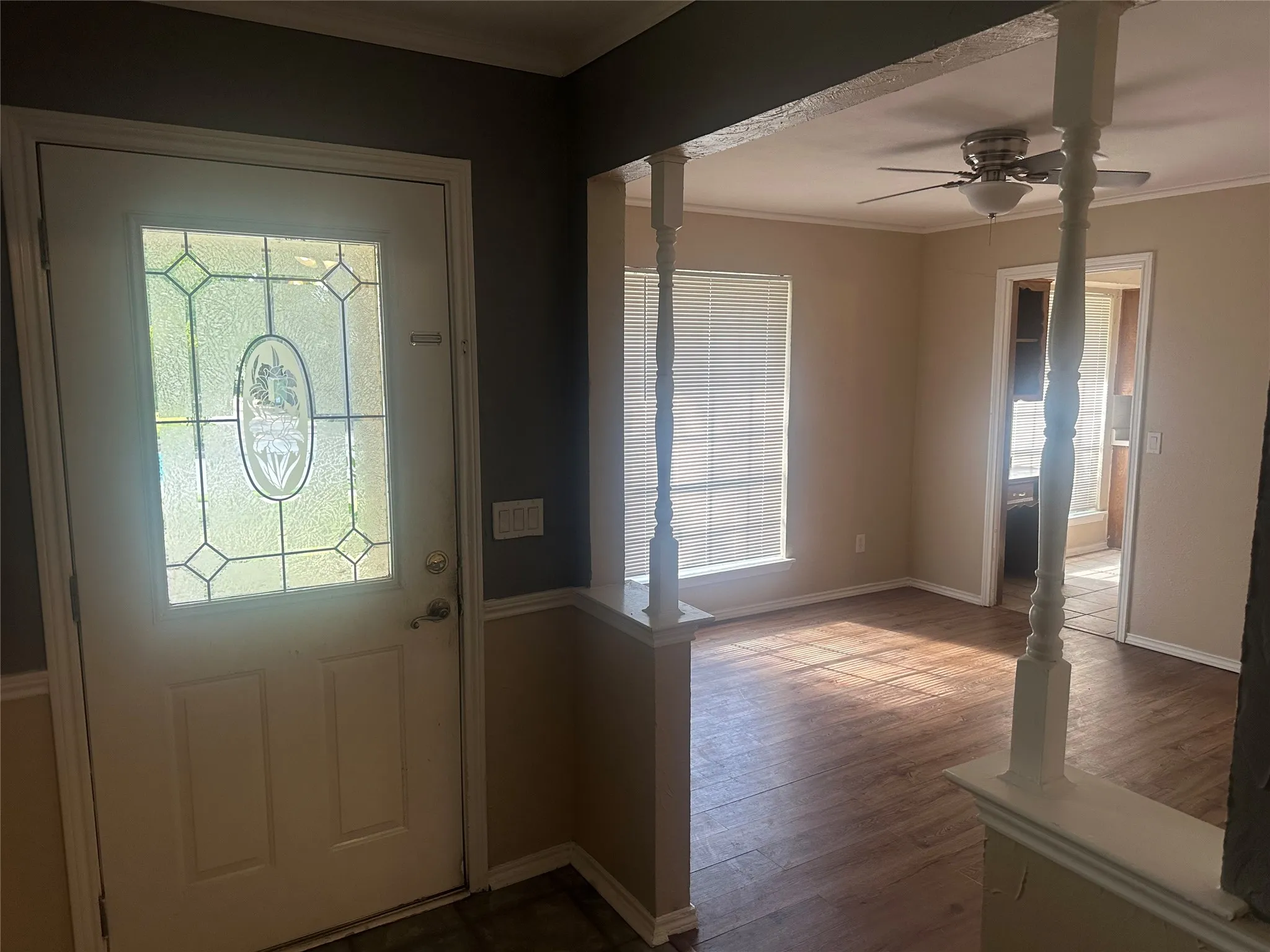 Entryway featuring a solid door with decorative glass paneling, wood-finish flooring, and white spindle columns on a half-wall partition