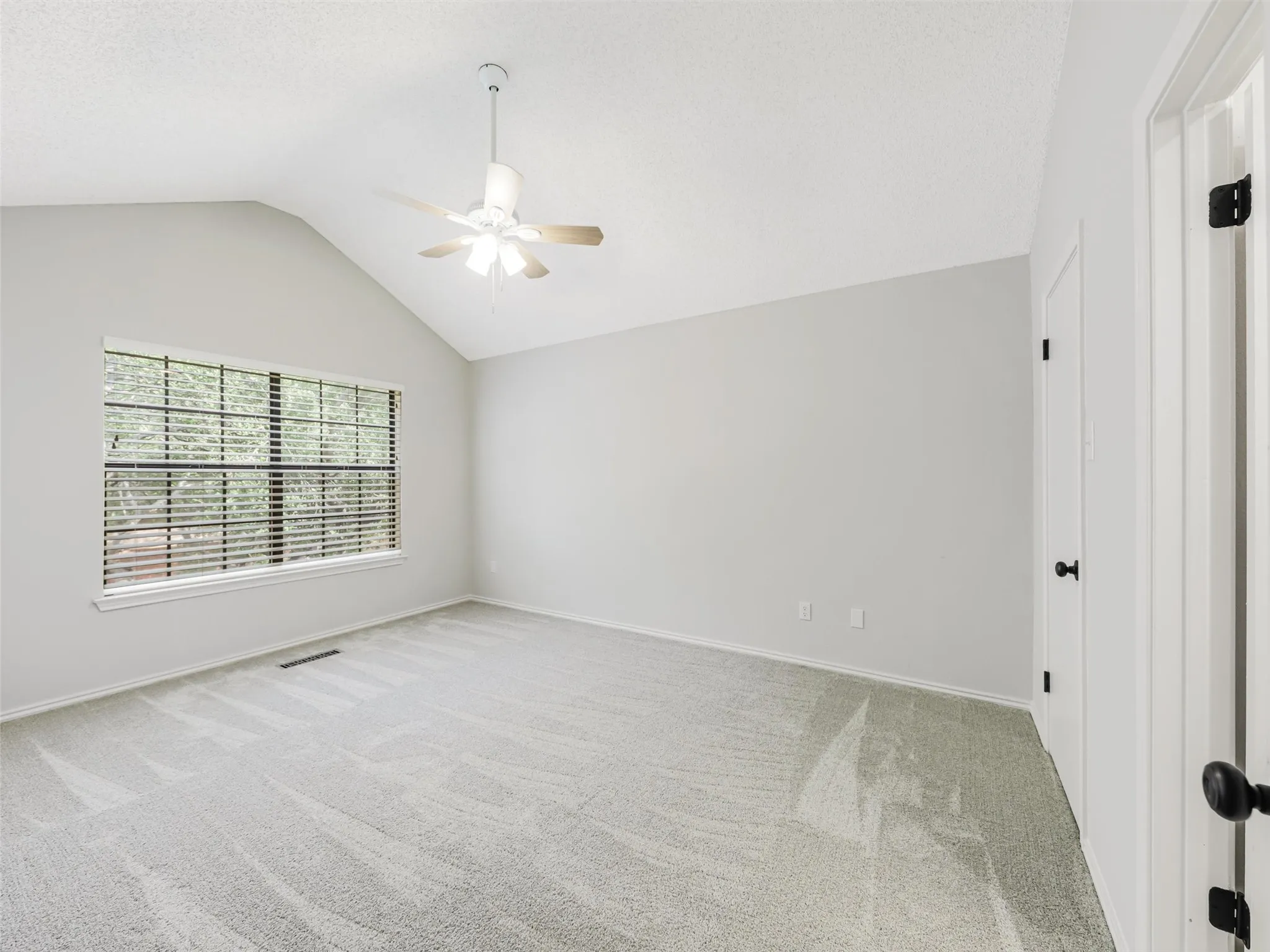 Vaulted ceiling, wall-to-wall carpeting, multi-pane window, and central ceiling fan with integrated lighting