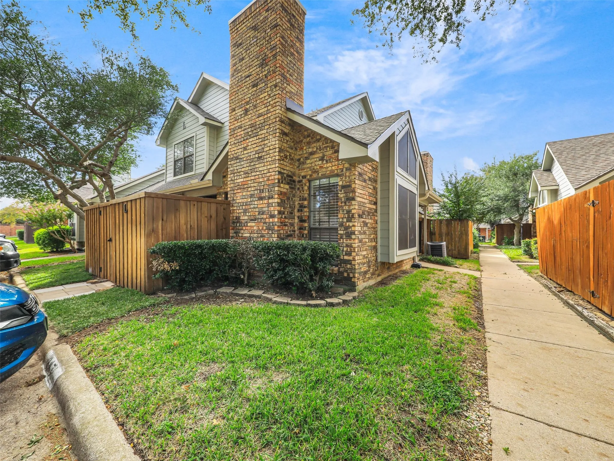 Multi-gabled exterior featuring a prominent full-height brick chimney, horizontal siding, and a concrete walkway
