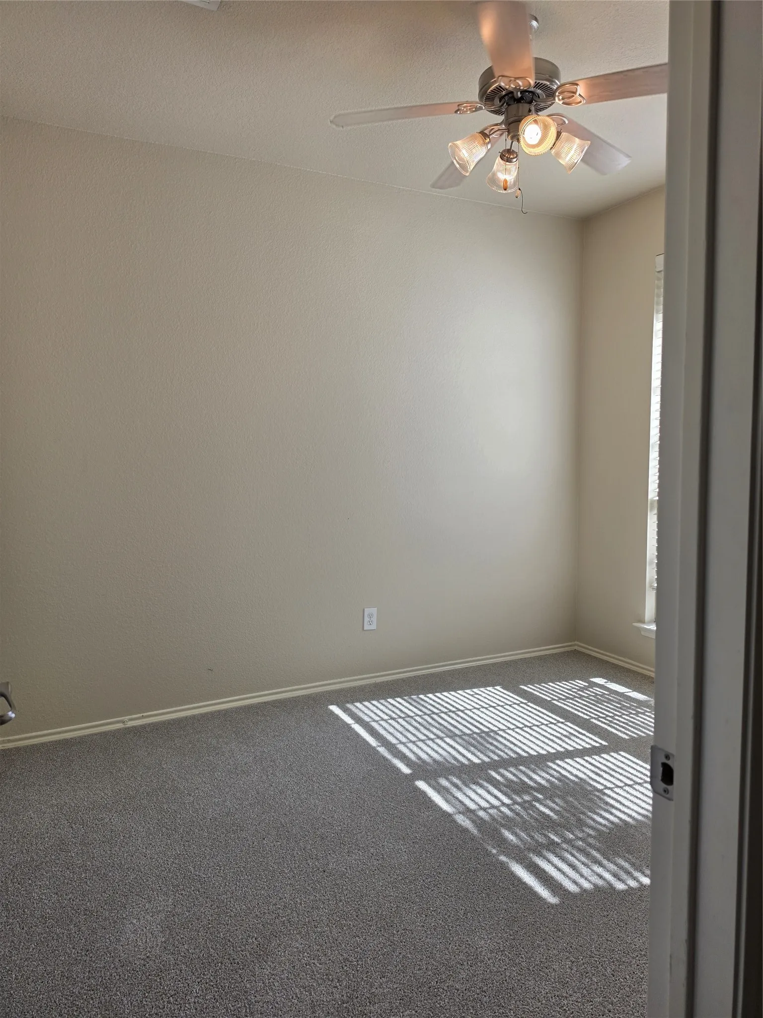Room featuring neutral wall tones, carpeted flooring, a ceiling fan with integrated lighting, and a window with horizontal blinds