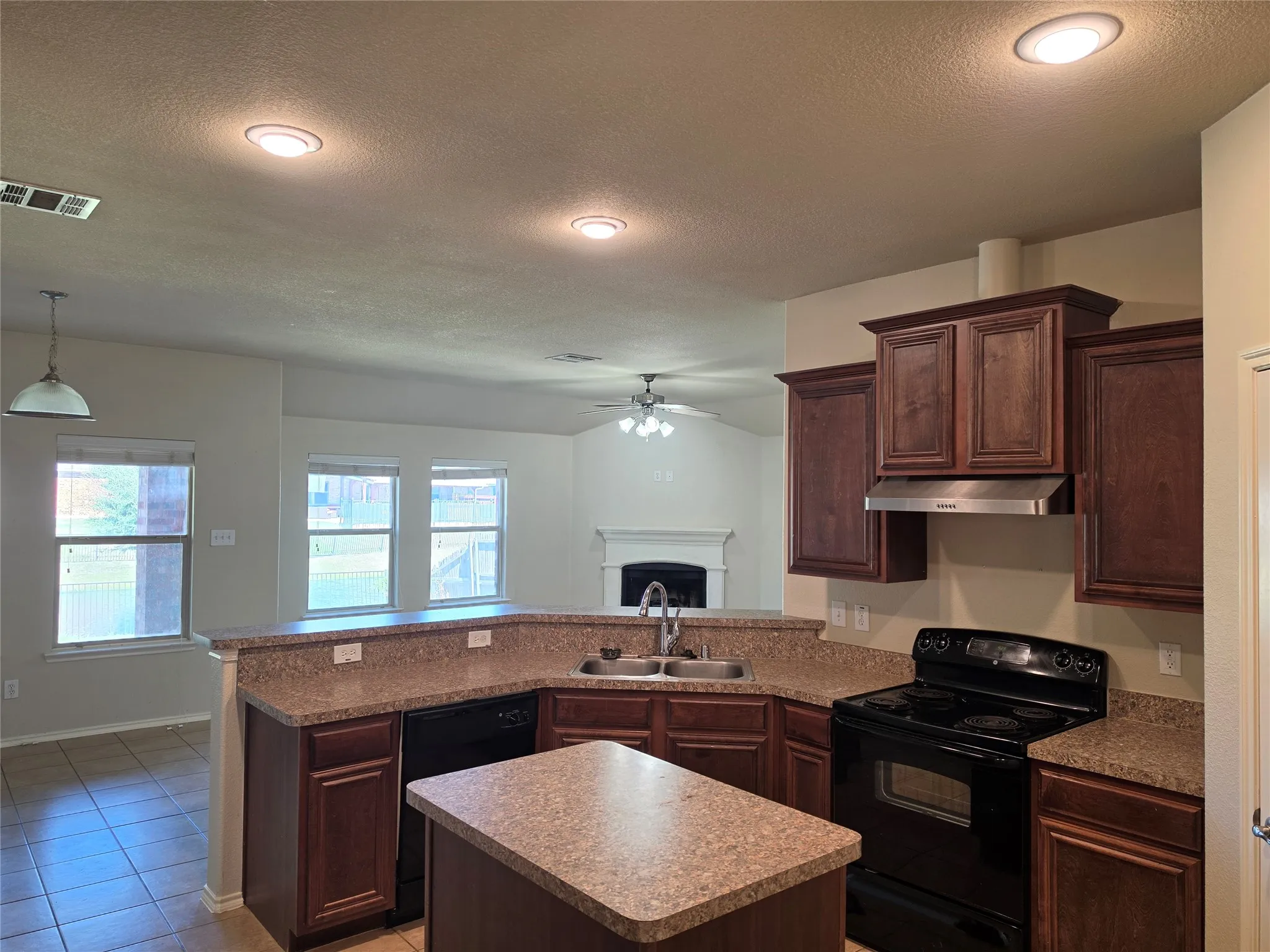 Kitchen featuring dark wood cabinetry, a center island with countertop seating, stone-composite countertops, stainless steel dual-basin sink, and recessed lighting
