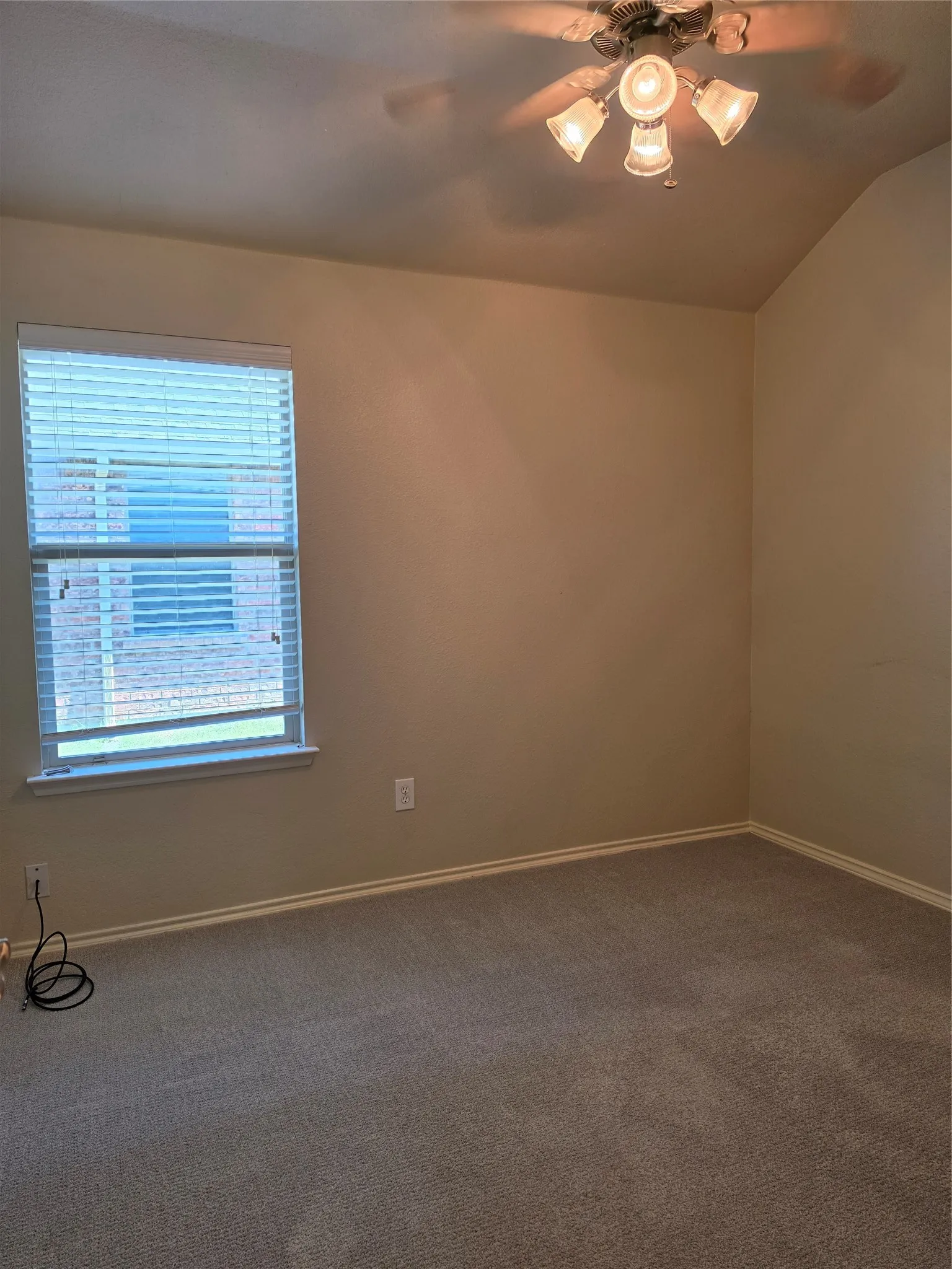 Room featuring neutral wall tones, neutral carpeting, vaulted ceiling, multi-light ceiling fan, and window with installed blinds