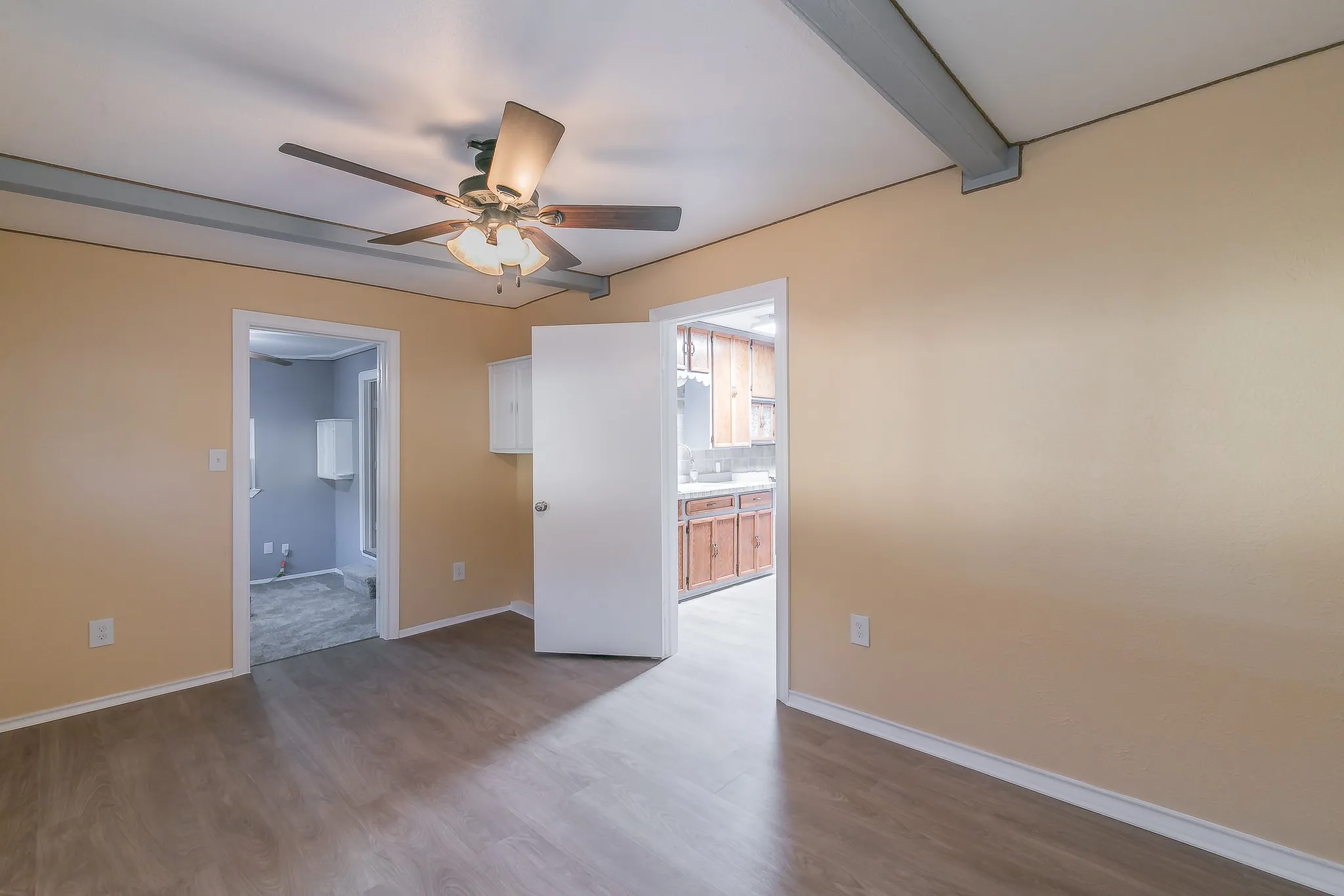 Unfurnished room featuring beam ceiling, ceiling fan, and hardwood / wood-style floors