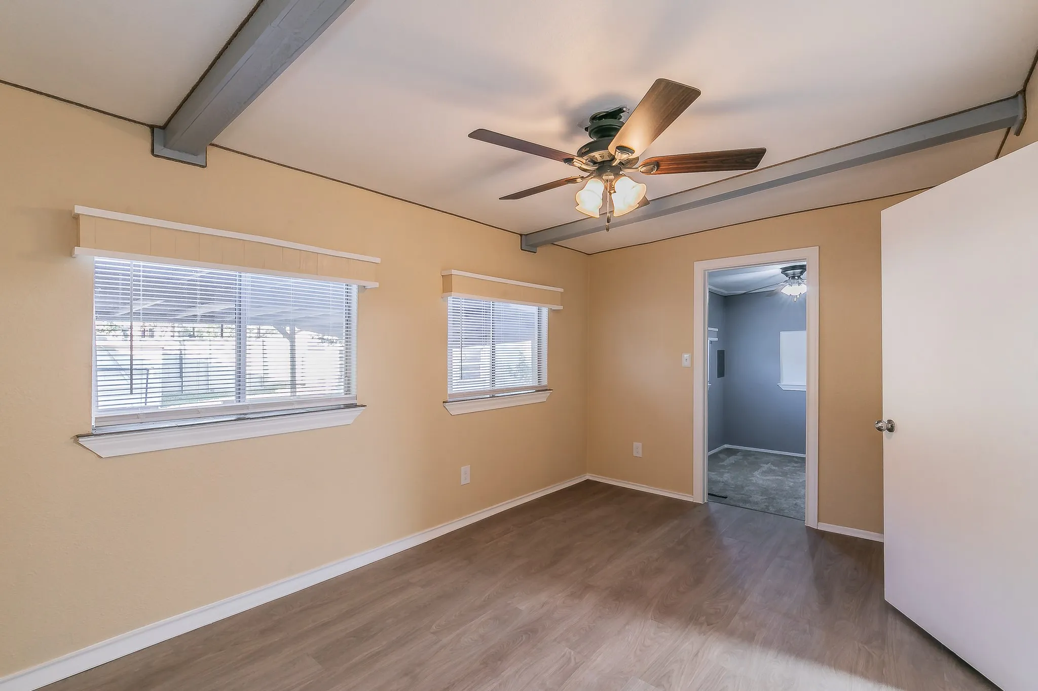 Spare room featuring hardwood / wood-style floors, ceiling fan, and beamed ceiling