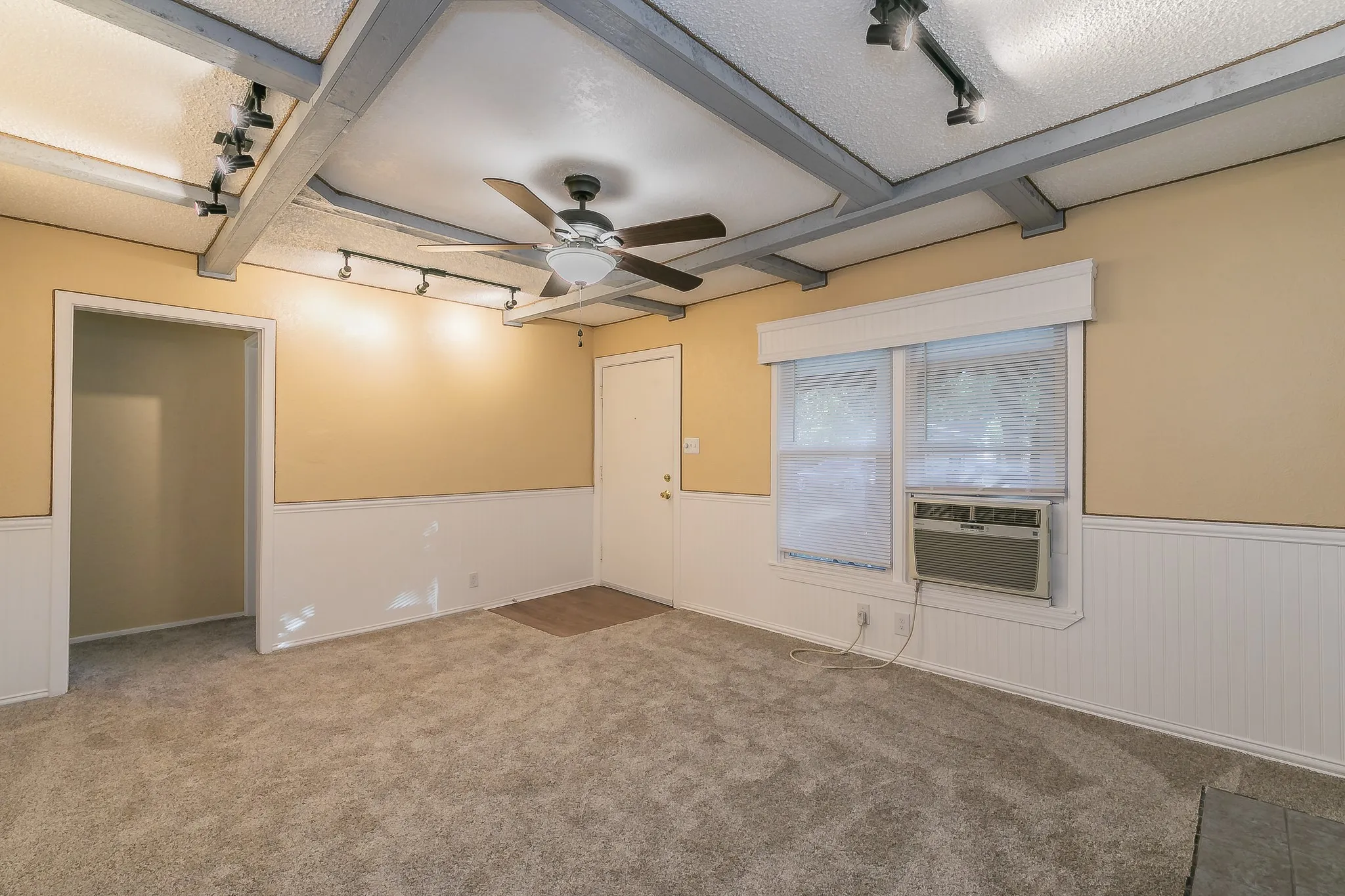 Carpeted spare room featuring beam ceiling, ceiling fan, and cooling unit