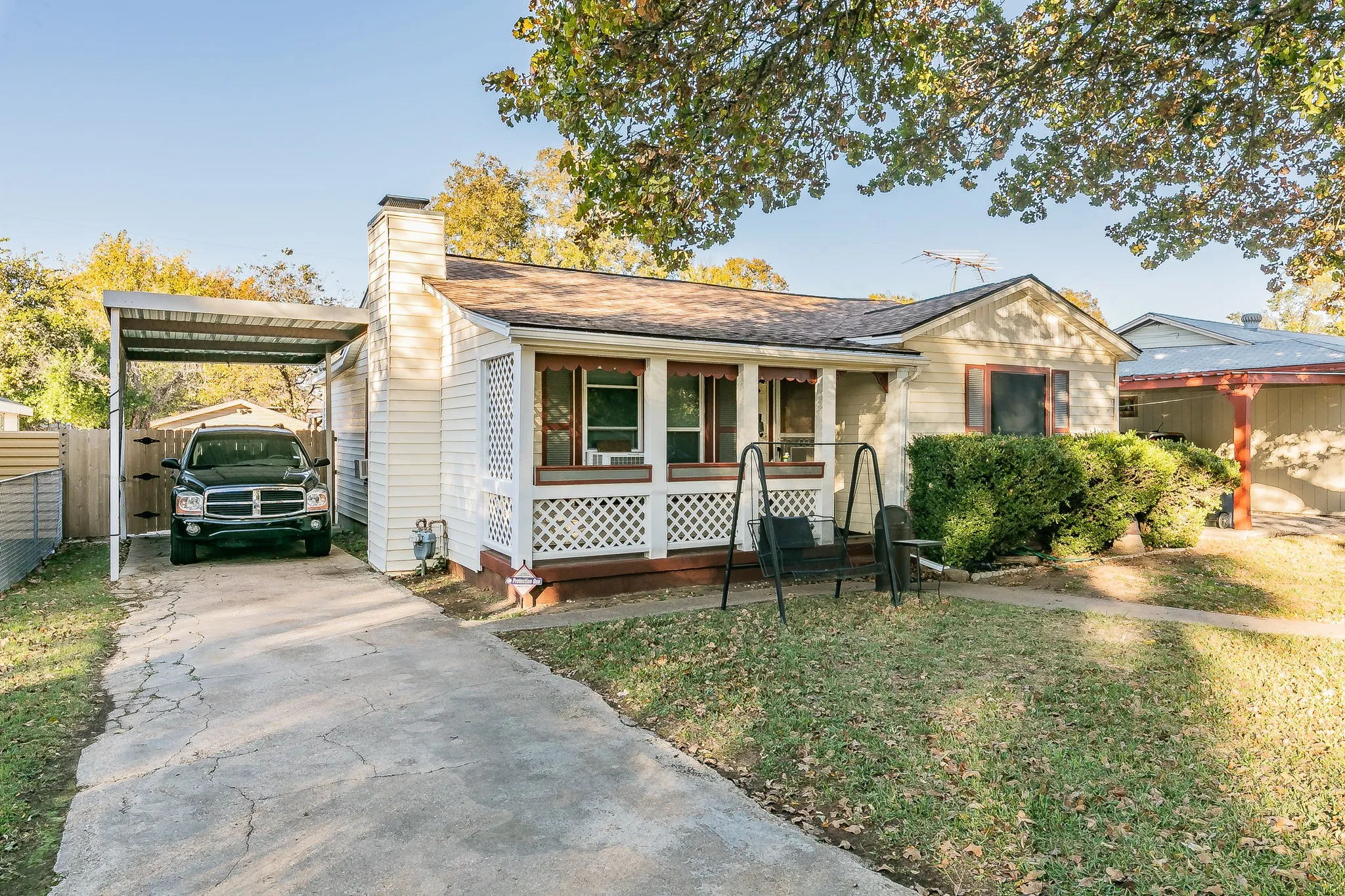Ranch-style house featuring a front lawn, a porch, and a carport