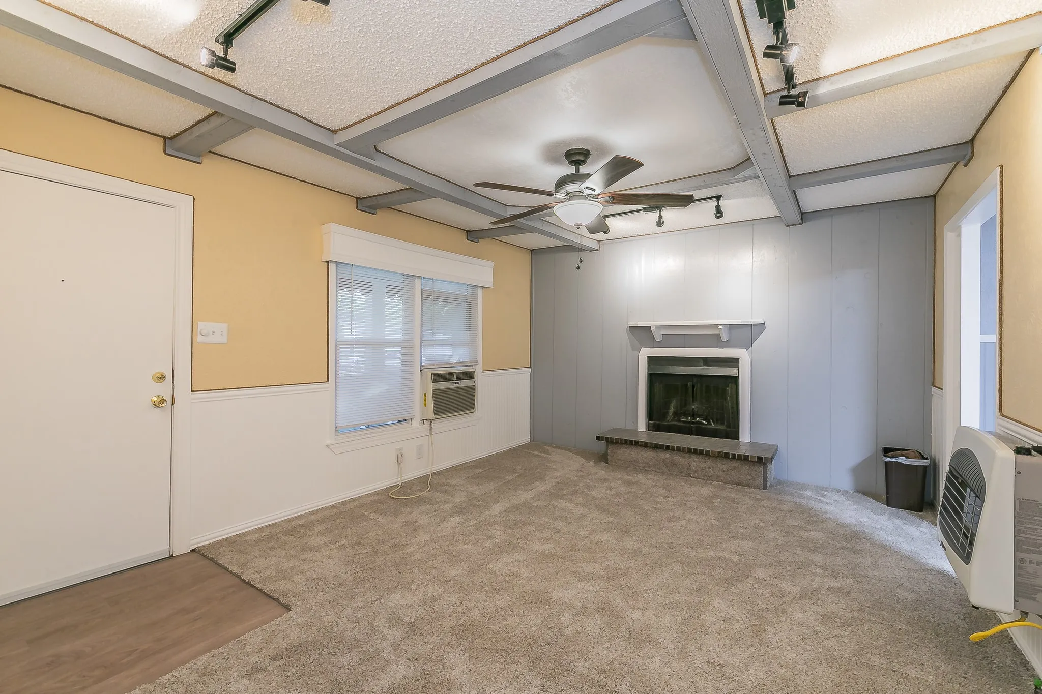 Unfurnished living room with light carpet, ceiling fan, a textured ceiling, beam ceiling, and heating unit